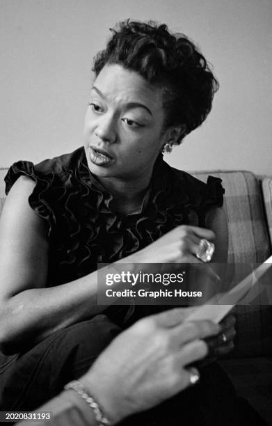 Trinidadian pianist and singer Hazel Scott, wearing a dark sleeveless ruffled top, discussing a document held by a person out of frame, at Frankfurt...