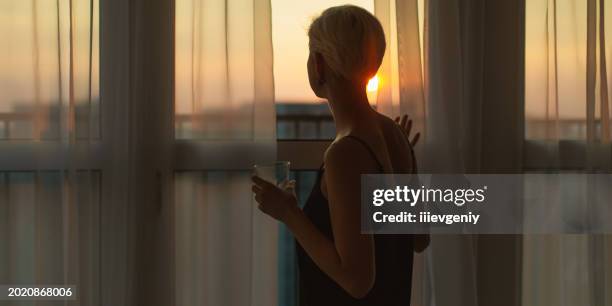 female silhouette against background of window at dusk. depressed woman - dark stock pictures, royalty-free photos & images