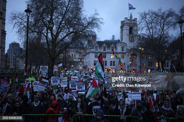 People hold placards and Palestinian flags during a rally calling for a ceasefire, outside parliament as MPs consider a motion on Gaza on February...