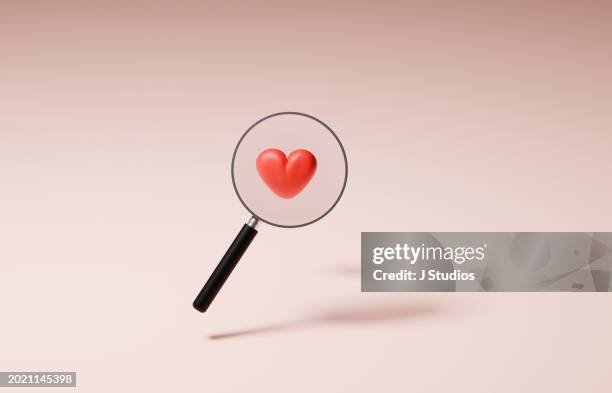 magnifier glass looking at red heart - red couple stockfoto's en -beelden