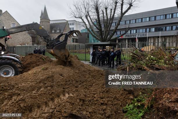 French riot Gendarmes mobiles stand by the fence as farmers use their tractors to pour soil in front of the Cotes-d'Armor prefecture building in...