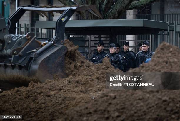 French riot Gendarmes mobiles stand by the fence as farmers use their tractors to pour soil in front of the Cotes-d'Armor prefecture building in...