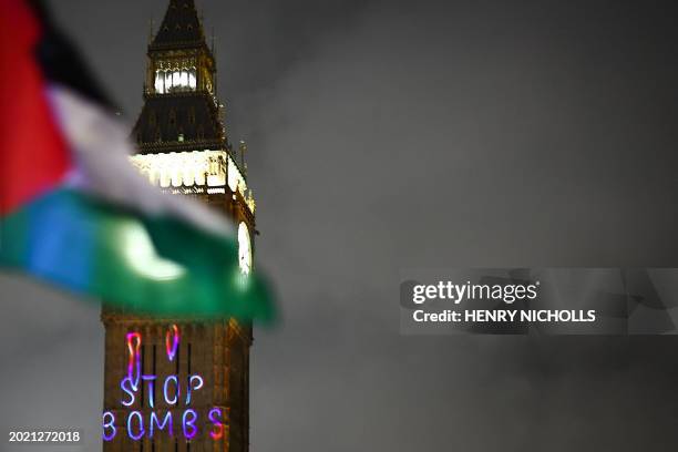 Palestinian flag flaps in the air by a message reading "Stop bombs" projected on The Elizabeth Tower, commonly known by the name of the clock's bell...