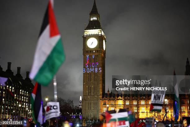 Palestinian flag flaps in the air by a message reading "Stop bombs" projected on The Elizabeth Tower, commonly known by the name of the clock's bell...
