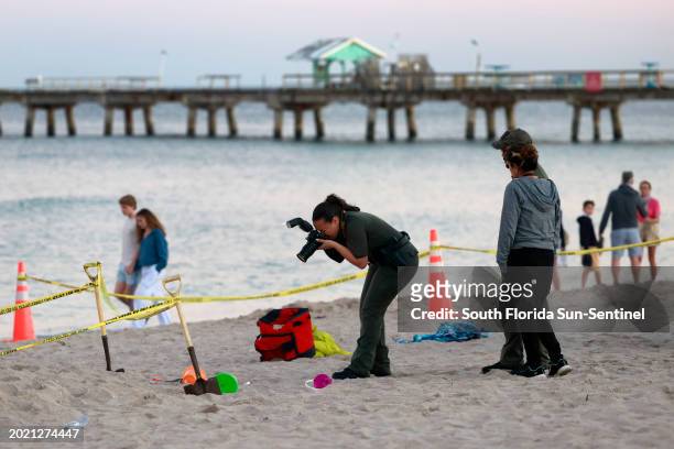 Investigators on the beach in Lauderdale-by-the-Sea take photos of the scene of a sand collapse on Tuesday, Feb. 20, 2024. A young girl died Tuesday...
