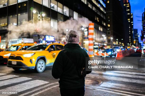 Person waits to cross the Lexington avenue in the Manhattan borough of New York on February 21, 2024.