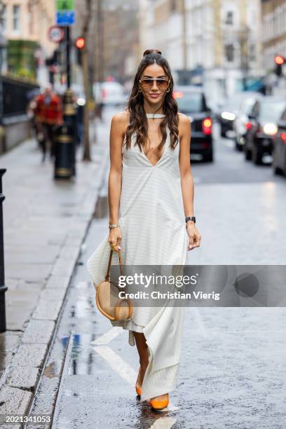 Tamara Kalinic wears white dress, beige bag, orange heels outside JW Anderson during London Fashion Week February 2024 on February 18, 2024 in...