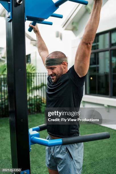 man does pull-ups on exercise equipment outside - ups stock pictures, royalty-free photos & images