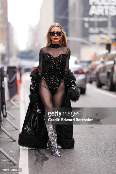 Guest wears sunglasses, earrings, lipstick , make-up, a black mesh bodysuit with black shiny glitter sequin parts , a black leather Balenciaga bag,...