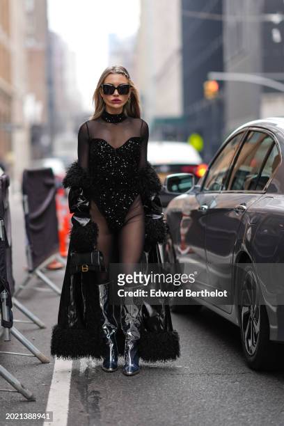 Guest wears sunglasses, earrings, lipstick , make-up, a black mesh bodysuit with black shiny glitter sequin parts , a black leather Balenciaga bag,...