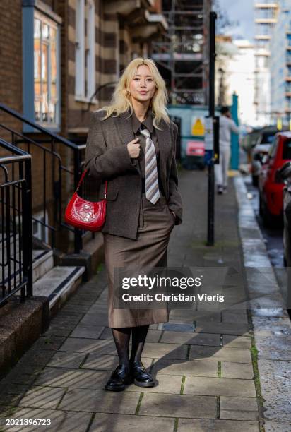 Betty Bachz wears brown jacket, tie, pants, shirt outside Eudon Choi during London Fashion Week February 2024 on February 18, 2024 in London, England.