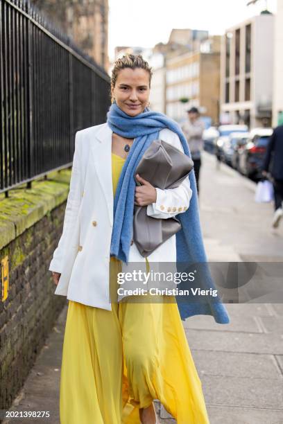 Mija Knezevic wears yellow dress, blue scarf, white blazer, brown bag outside Eudon Choi during London Fashion Week February 2024 on February 18,...