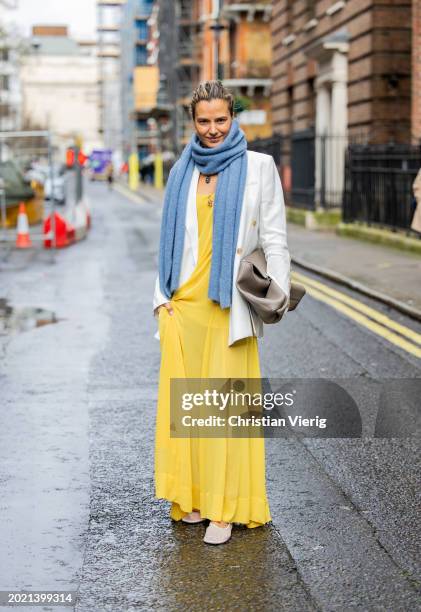 Mija Knezevic wears yellow dress, blue scarf, white blazer, brown bag outside Eudon Choi during London Fashion Week February 2024 on February 18,...