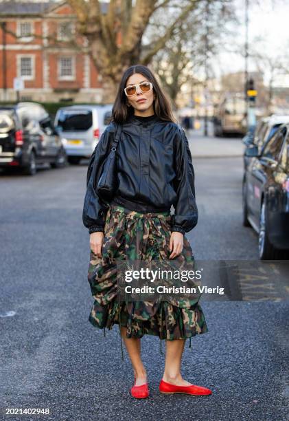 Gabrielle Dyer wears camouflage skirt, black jacket, red shoes outside Holzweiler during London Fashion Week February 2024 on February 18, 2024 in...