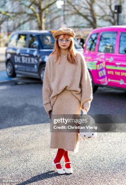 Guest wears MCM rabbit bag, beige skirt, knit, red tights outside Holzweiler during London Fashion Week February 2024 on February 18, 2024 in London,...