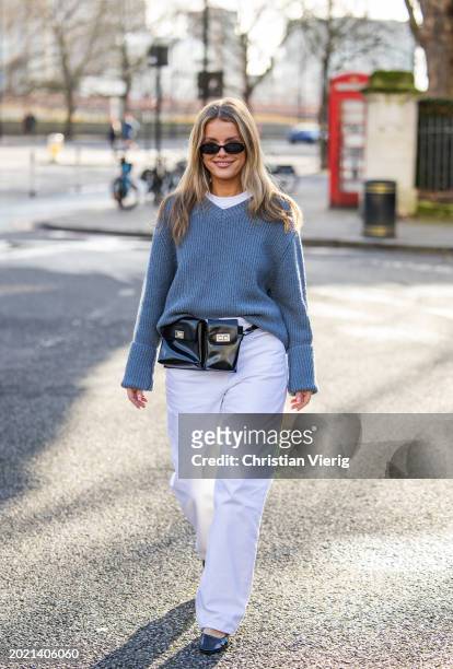 Josefine Vogt wears grey v neck knit, black belt bag, white pants outside Holzweiler during London Fashion Week February 2024 on February 18, 2024 in...