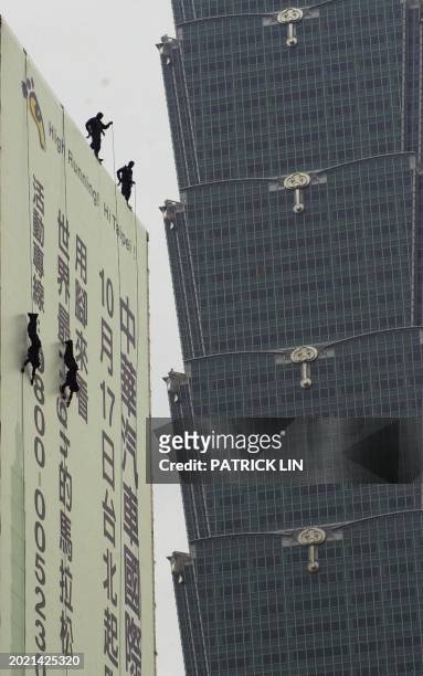 Team of Taiwanese policemen rappel from the wall of the city hall next to the world's tallest building Taipei 101 during an anti-terrorist drill in...