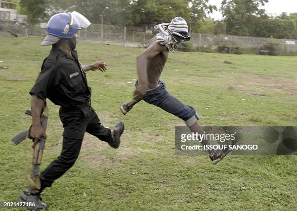 An Ivorian policeman tries to arrest a demonstrator who was throwing stones to French gendarmes 05 October 2004 during a protest at the French...