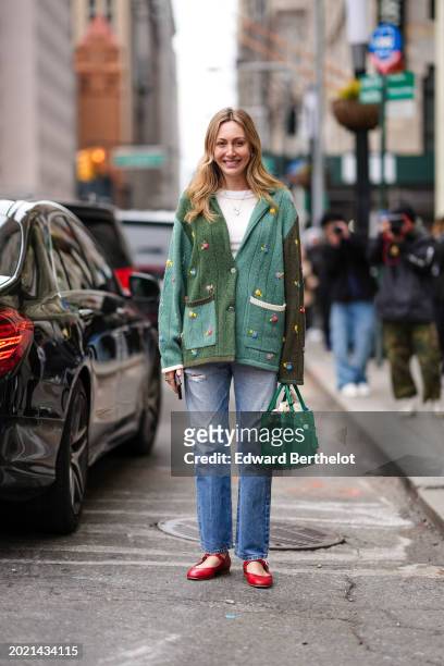 Guest wears a necklace, white t-shirt, a green oversized cardigan with attached colored details, a green leather bag from Prada, blue ripped denim...