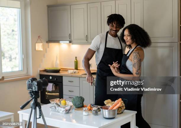 una pareja filmando un vlog en su cocina - plano fijo fotografías e imágenes de stock