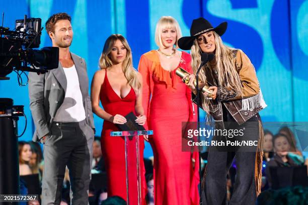 Pictured: Lainey Wilson accepts The Female Country Artist of the Year award from Glen Powell, Sydney Sweeney, and Natasha Bedingfield onstage during...