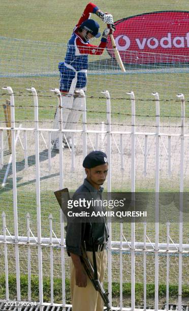 England's cricket captain Michael Vaughan plays a shot as a Pakistani policeman keeps tight vigil during the net session at Pindi cricket stadium in...