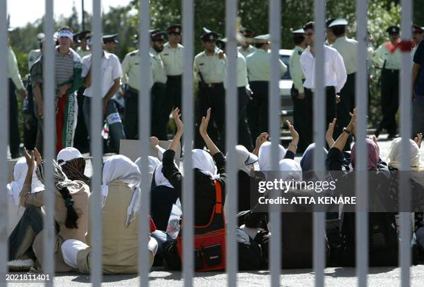 Iranian policemen stand guard in front of women clapping hands as they try to get into the stadium to watch the Asian qualifying match against...