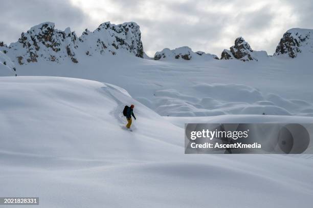 backcountry snowboarder descends mountain - nordic skiing stock pictures, royalty-free photos & images