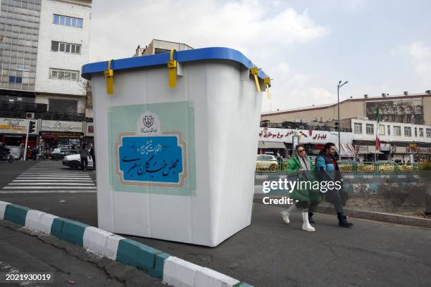 People walk past an installation of a ballot box during the first day of election campaign in Tehran, on February 22 ahead of next month's elections....