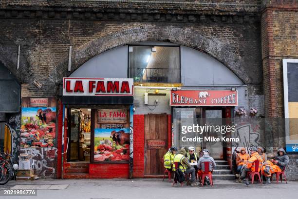 Construction workers take a break outside Elephant Coffee next to La Fama Colombian butchers shop at Elephant and Castle on 7th February 2024 in...