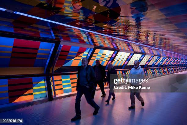 People interacting with the geometric public contemporary artwork 'Captivated by Colour' by artist Camille Walala in the tunnel walkway at Adams...