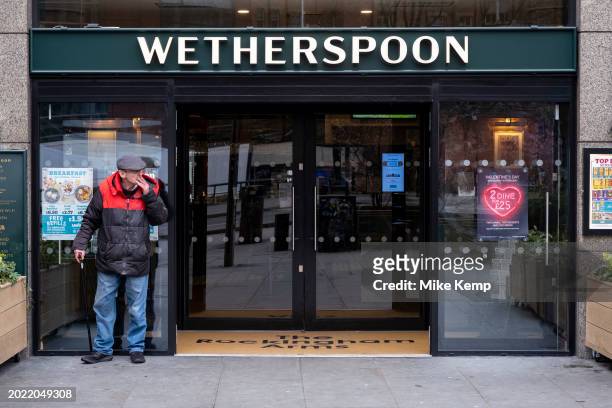 Customer having a cigarette outside Wetherspoons pub The Rockingham Arms at Elephant and Castle on 7th February 2024 in London, United Kingdom. J D...