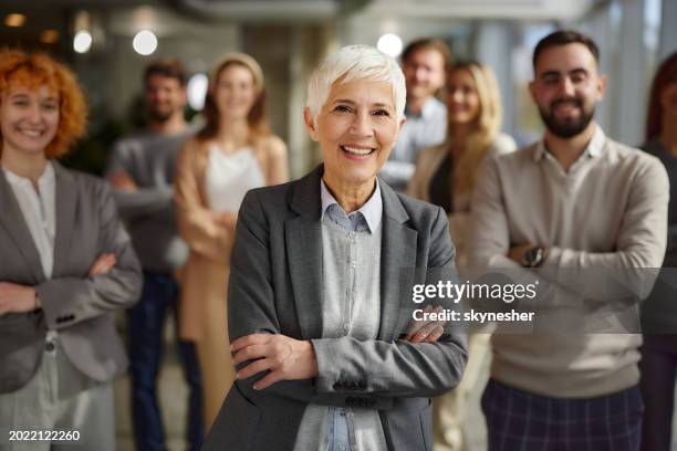 happy senior ceo in front of her team in the office. - senior management stock pictures, royalty-free photos & images