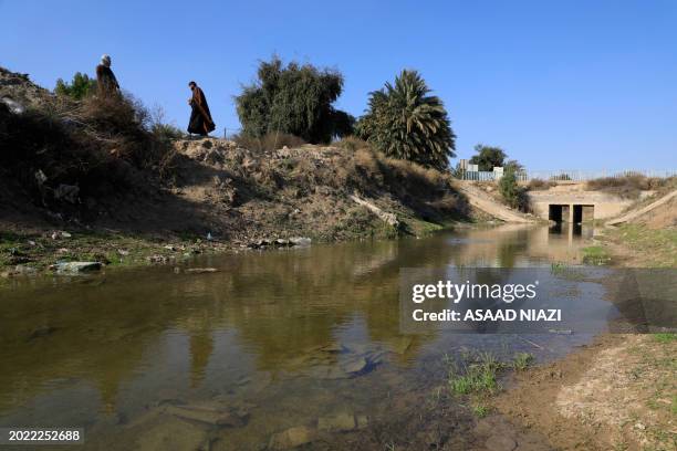 Iraqi villagers walk past the river of al-Qasr on the outskirts of the village of Kenana in southern Iraq's dry al-Gharraf district, which suffers...