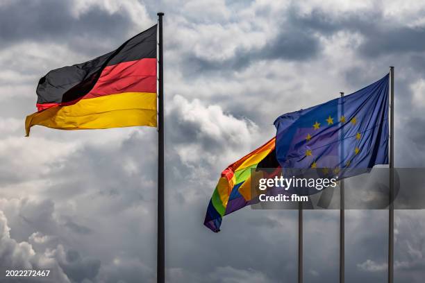 german-, eu- and rainbow (lgbtq+)- flag with storm clouds in the sky - berlin gay pride stock pictures, royalty-free photos & images
