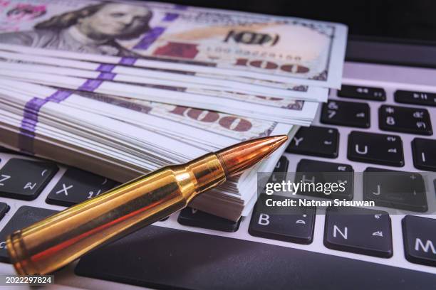 rifle bullet on keyboard with stock chart going down background. - gun and money stock pictures, royalty-free photos & images