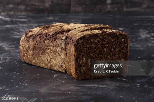 rye black bread with seeds on dark board background - rye grain stockfoto's en -beelden