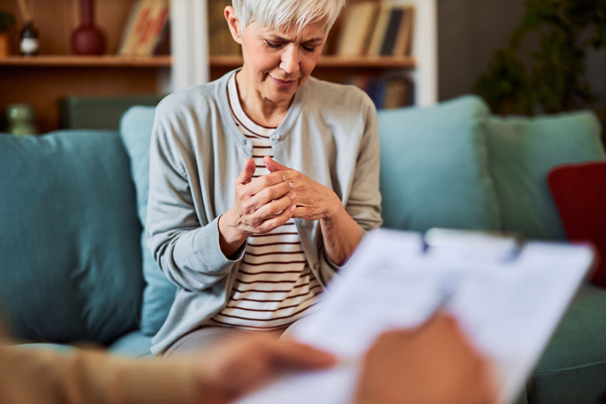 A depressed mature woman in despair fidgeting with her fingers with her eyes closed while sitting in the doctor's office A depressed mature woman in despair fidgeting with her fingers with her eyes closed while sitting in the doctor's office