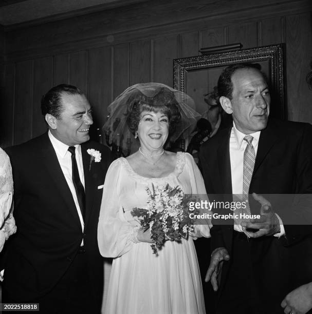 American actor Ernest Borgnine with his wife, American actress and singer Ethel Merman, who wears her wedding dress and holds a small bouquet, and...