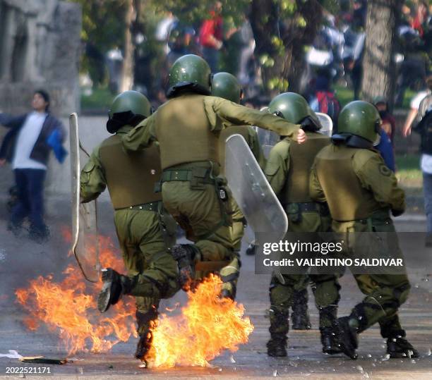 Policia de las fuerzas especiales chilenas saltan para evitar algunas bombas incendiarias durante una protesta en Santiago de 10 de mayo de 2006. La...