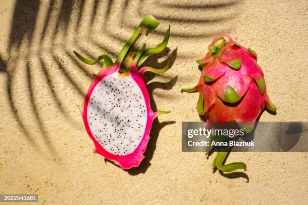 halved dragon fruit close-up in bright day sun light on yellow background - pitaya stock pictures, royalty-free photos & images