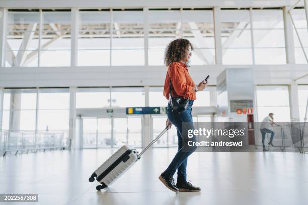 woman walking at the airport with suitcase - african american people stock pictures, royalty-free photos & images