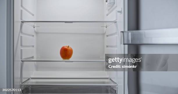 gros plan d’une pomme rouge dans un réfrigérateur - réfrigérateur vide photos et images de collection