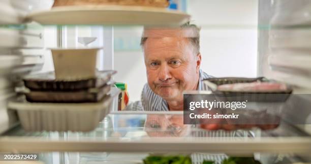 frowning man looking slice of empty fridge - koelkast stockfoto's en -beelden