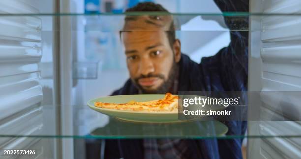 frowning man looking slice of pizza - pizza temptation stock pictures, royalty-free photos & images