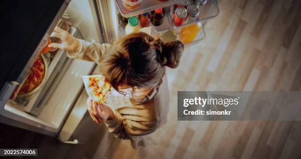 mature woman eating pizza at home - pizza temptation stock pictures, royalty-free photos & images