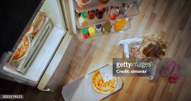 girl eating pizza at home - pizza temptation stock pictures, royalty-free photos & images