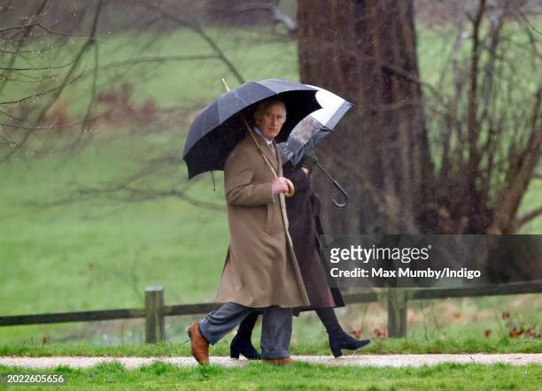 King Charles III and Queen Camilla shelter under umbrellas as they attend the Sunday service at the Church of St Mary Magdalene on the Sandringham...