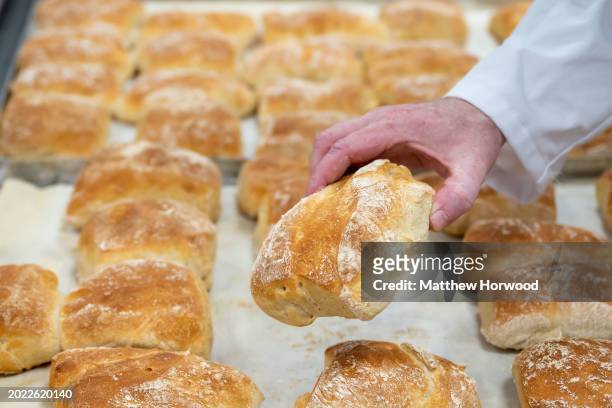 Man holds a bread roll in a bakery on November 14, 2023 in Cardiff, Wales.