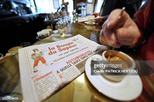 Une personne boit un café dans une brasserie, le 29 février 2008 à Paris, à côté de "La Bougie du Sapeur", le quotidien humoristique lancé en 1980...